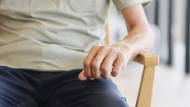 Elderly Asian man with trembling hands due to Parkinson's disease