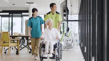 Elderly people and caregivers walking in wheelchairs
