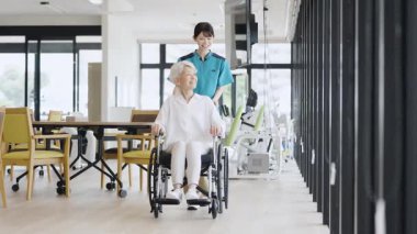 Elderly people and caregivers walking in wheelchairs