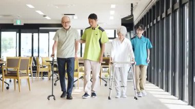 Asian caregiver supporting elderly people walking