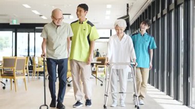 Asian caregiver supporting elderly people walking