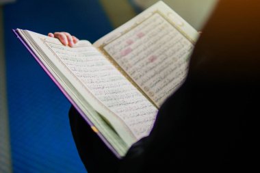 Cami içinde Kur'an-ı Kerim okuyan Müslüman kadının yakından görünümü