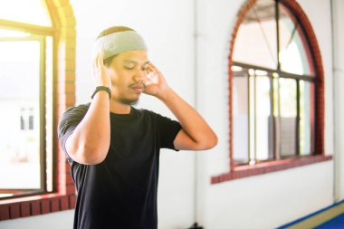 Genç Müslüman bir adam camide Takbir için dua ediyor.