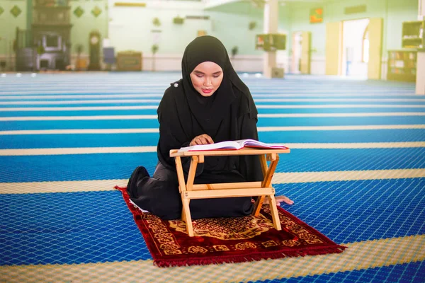 Ung muslimsk kvinna reciterar al-Quran i en moské. Al Quran är en islamisk helig bok — Stockfoto