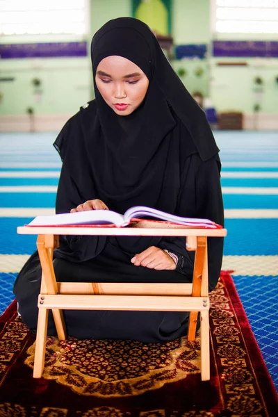 Jeune femme musulmane récitant le Coran dans une mosquée. Le Coran est un livre sacré islamique — Photo