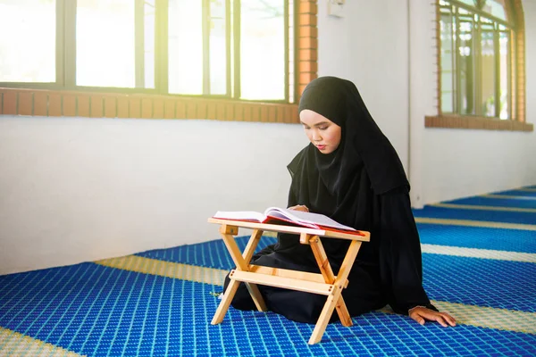 Jonge moslimvrouw die Al Quran voordraagt in een moskee. Al-Koran is een islamitisch bijbelboek — Stockfoto