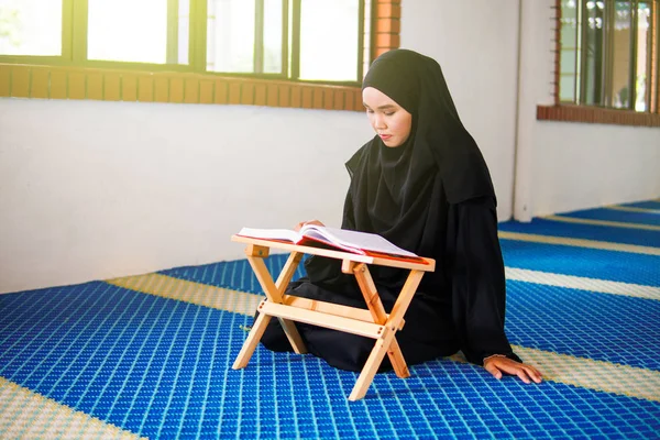 Jonge moslimvrouw die Al Quran voordraagt in een moskee. Al-Koran is een islamitisch bijbelboek — Stockfoto