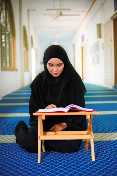 Jeune femme musulmane récitant le Coran dans une mosquée. Le Coran est un livre sacré islamique — Photo