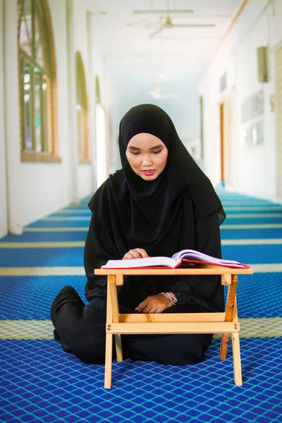 Jeune femme musulmane récitant le Coran dans une mosquée. Le Coran est un livre sacré islamique — Photo