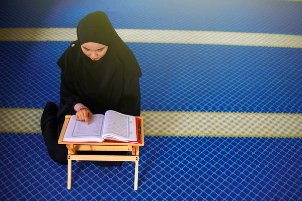 Jonge moslimvrouw die Al Quran voordraagt in een moskee. Al-Koran is een islamitisch bijbelboek — Stockfoto