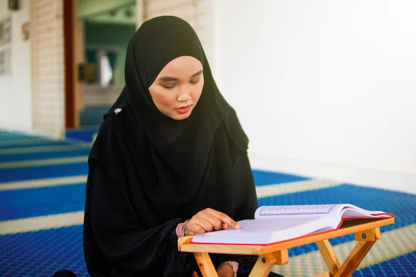 Jeune femme musulmane récitant le Coran dans une mosquée. Le Coran est un livre sacré islamique — Photo