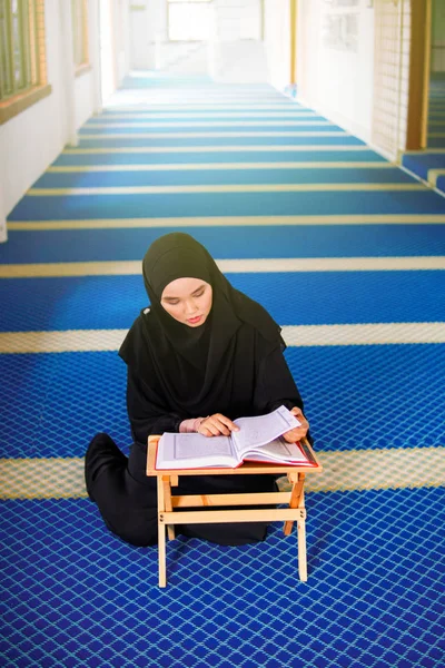 Молода жінка-муслім, що читає Аль-Корану в мечеті. Аль-Коран - ісламська священна книга — стокове фото