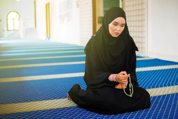 Mujer musulmana joven rezando, dzikir a Allah mientras sostiene una perla de oración dentro de una mezquita — Foto de Stock