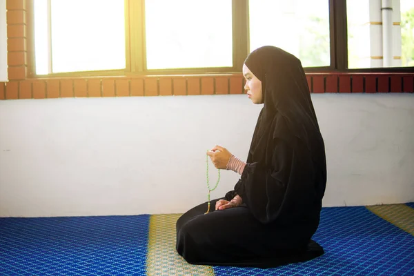 Jeune femme musulmane priant, dzikir à Allah tout en tenant une perle de prière à l'intérieur d'une mosquée — Photo