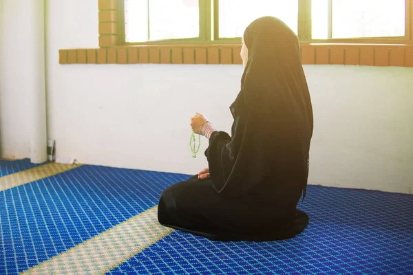 Jovem mulher muçulmana orando, dzikir a Deus, enquanto segurando uma pérolas de oração dentro de uma mesquita — Fotografia de Stock