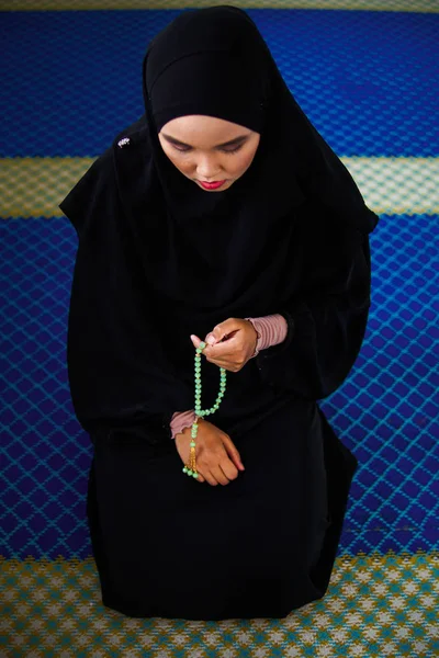 Mujer musulmana joven rezando, dzikir a Allah mientras sostiene una perla de oración dentro de una mezquita — Foto de Stock