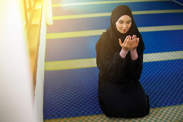 Jovem mulher muçulmana orando a Deus com as mãos para cima dentro de uma mesquita — Fotografia de Stock