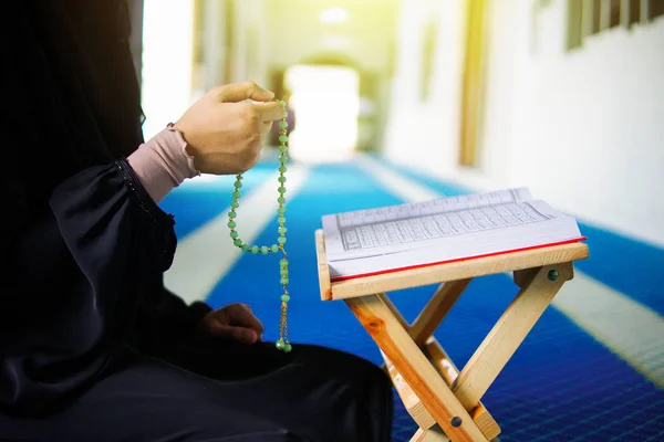 Vista lateral de la joven musulmana dzikir a Allah en la alfombra de oración con la mano sosteniendo cuentas dentro de una mezquita —  Fotos de Stock