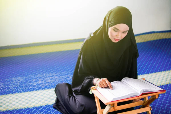 Ung muslimsk kvinna reciterar al-Quran i en moské. Al Quran är en islamisk helig bok — Stockfoto