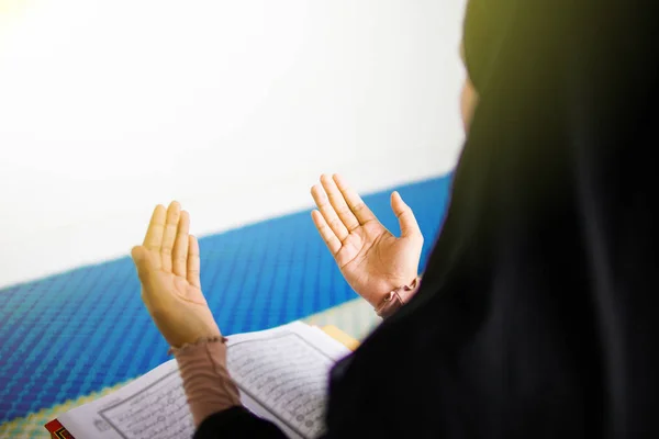 Mujer musulmana joven rezando a Allah con las manos en alto delante del Sagrado Corán dentro de una mezquita — Foto de Stock