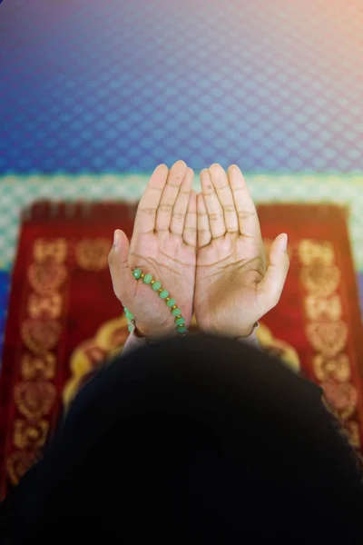 Visão próxima da mulher muçulmana orando a Deus com as mãos para cima no tapete de oração, segurando contas — Fotografia de Stock