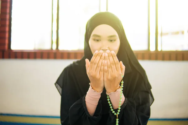 Jovem mulher muçulmana orando a Deus com as mãos no tapete de oração, segurando contas — Fotografia de Stock
