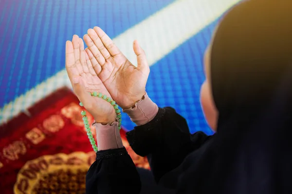 Nahaufnahme einer muslimischen Frau, die mit erhobenen Händen auf einer Gebetsmatte zu Allah betet und Perlen in der Hand hält — Stockfoto