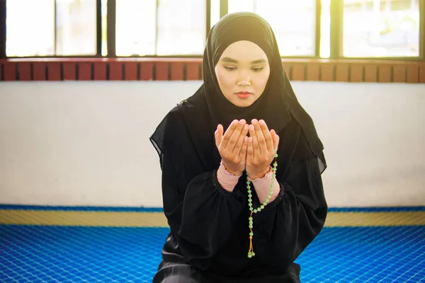 Jovem mulher muçulmana orando a Deus com as mãos no tapete de oração, segurando contas — Fotografia de Stock