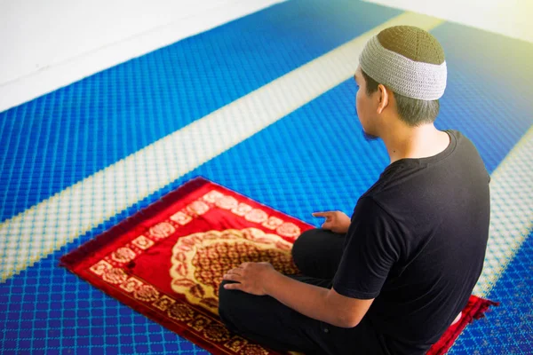 イスラム教徒の男性が祈り、モスクの中で祈るマットの上に1本の指で — ストック写真