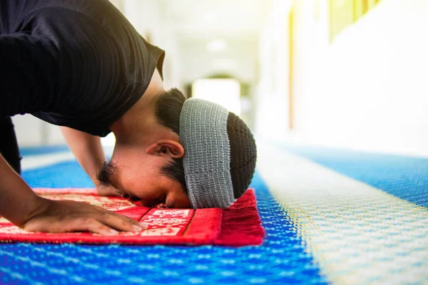 Primo piano dell'uomo musulmano religioso che prega, prostrandosi sul tappeto di preghiera all'interno della moschea — Foto Stock