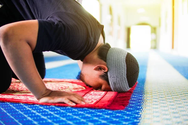 Primo piano dell'uomo musulmano religioso che prega, prostrandosi sul tappeto di preghiera all'interno della moschea — Foto Stock