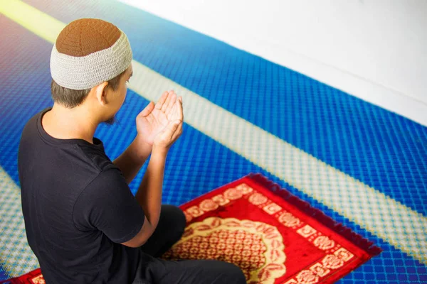 Vista superior del hombre musulmán haciendo du 'a rezando en alfombra de oración dentro de una mezquita — Foto de Stock