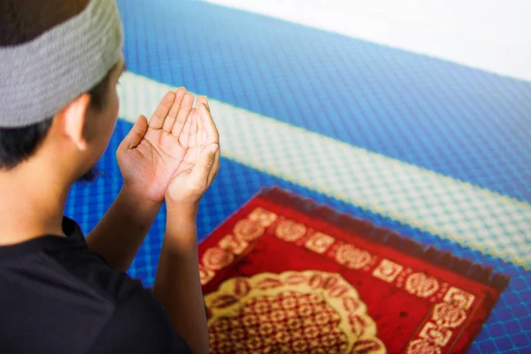 Vista superior del hombre musulmán haciendo du 'a rezando en alfombra de oración dentro de una mezquita — Foto de Stock