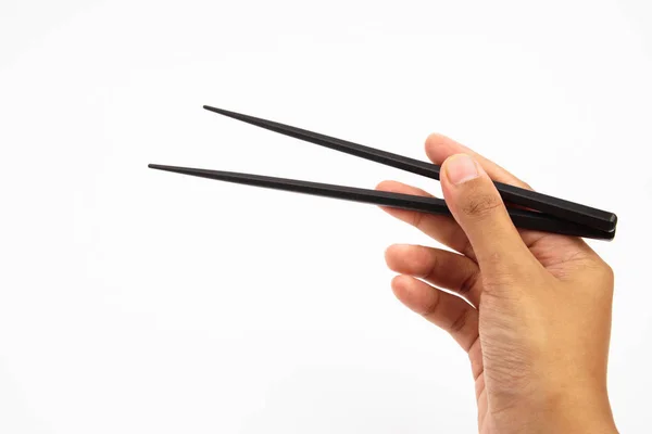 Рука, що тримає чорні дерев'яні палички ізольовані на білому тлі — стокове фото