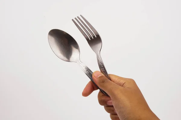 A hand holds steel silver fork and spoon isolated on white background — Stock Photo, Image