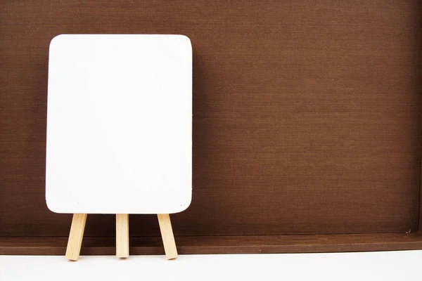 Mini chevalet en bois avec tableau blanc vierge isolé sur fond de texture en bois . — Photo