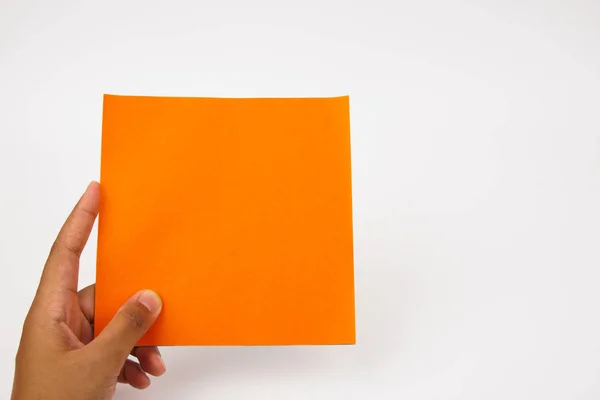 Une main tient du papier orange blanc sur un fond blanc . — Photo