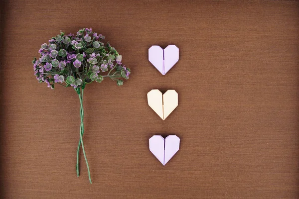 Mise en page créative faite de bouquet de fleurs violettes et un coeur en papier origami — Photo