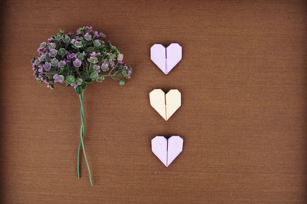 Mise en page créative faite de bouquet de fleurs violettes et un coeur en papier origami — Photo