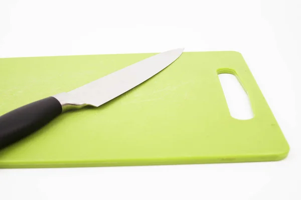 Vista superior de un cuchillo sobre una tabla de cortar verde con un fondo blanco. Concepto de cocina . —  Fotos de Stock