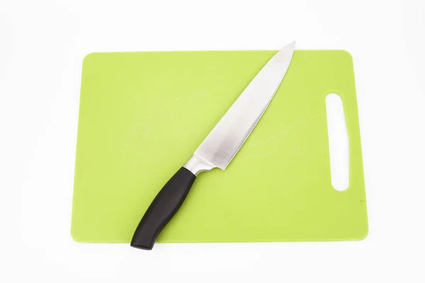 Beyaz arka planlı yeşil kesme tahtası üzerinde bir bıçak üst görünümü. Pişirme konsepti. — Stok fotoğraf