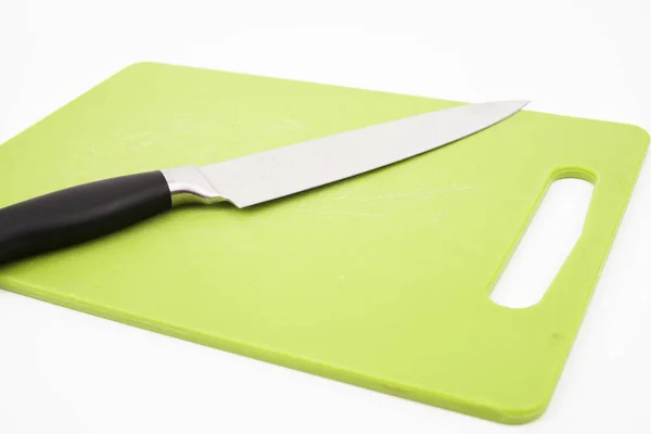 Beyaz arka planlı yeşil kesme tahtası üzerinde bir bıçak üst görünümü. Pişirme konsepti. — Stok fotoğraf