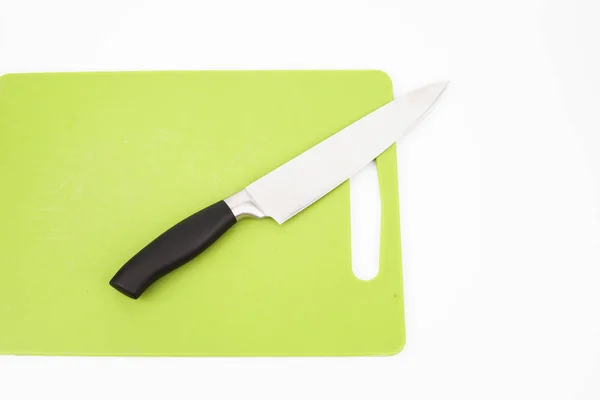 Vista superior de un cuchillo sobre una tabla de cortar verde con un fondo blanco. Concepto de cocina . —  Fotos de Stock