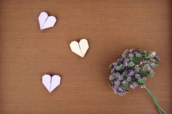 Mise en page créative faite de bouquet de fleurs violettes et un coeur en papier origami — Photo