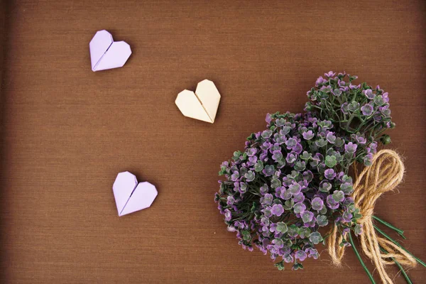 Mise en page créative faite de bouquet de fleurs violettes et un coeur en papier origami — Photo