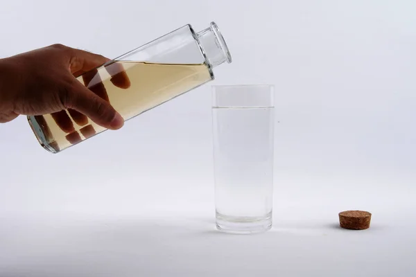 Eine Hand gießt eine Flasche schmutziges Wasser in ein mit sauberem Wasser gefülltes Glas auf weißem Hintergrund — Stockfoto