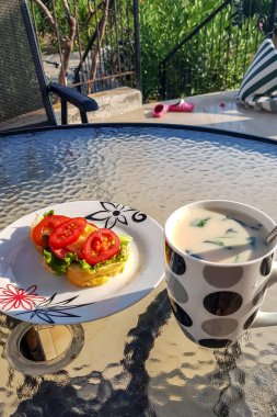Kahvaltıda sandviç ve bir fincan taze otlu yoğurt..