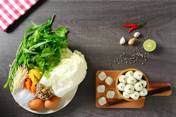 Tay gıda, kireç, biber, sarımsak ve çeşitli sebzeler, beyaz çanak ve ahşap kase balık topları üzerinde iki yumurta Malzemeler, ahşap masada üst görünümü.
