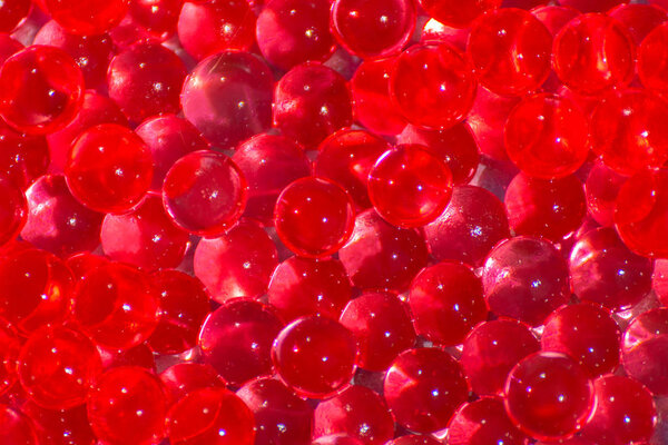 Transparent red hydrogel balls. Red water gel balls with bokeh. Polymer gel Silica gel. Liquid crystal ball with reflection. Red balls texture background