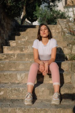 Genç kız çok utangaç gülümseyen ve merdivenlerde oturan